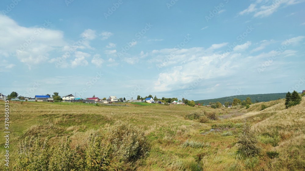 panoramic scene with countryside against a blue sky with clouds