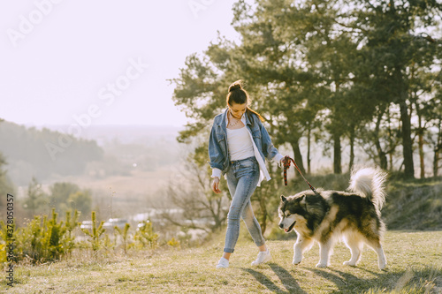 Woman in a spring forest. Girl with cute dog. Brunette in a jeans jacket. © prostooleh