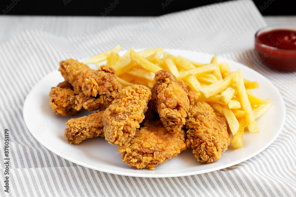 Homemade Crispy Chicken Wings and French Fries on a white plate, side view. Close-up. Homemade Crispy Chicken Wings and French Fries on a white plate, side view. Close-up.