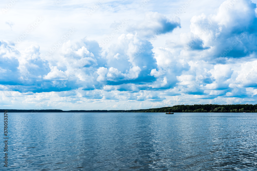 Multi-layered cumulus clouds over a blue lake in cloudy weather