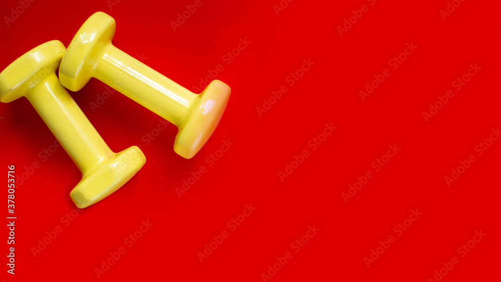 two yellow dumbbells on red background.wide banner two yellow dumbbells on red background.wide banner