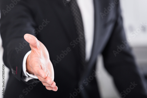 Successful businessman standing in office with open hand ready for handshake