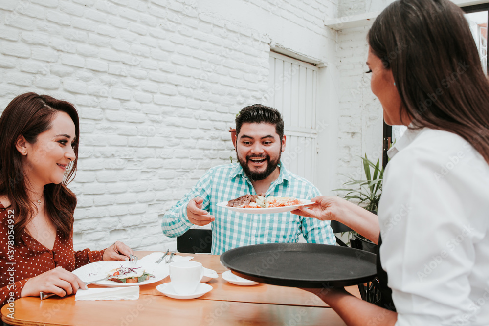 Owner mexican female waitress serving food to people sitting at restaurant in Latin america Owner mexican female waitress serving food to people sitting at restaurant in Latin america