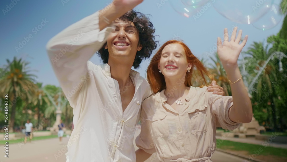 Portrait of love couple catching soap bubbles. Romantic man and woman having fun Portrait of love couple catching soap bubbles. Romantic man and woman having fun
