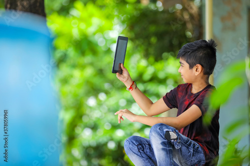 Indian / Asian Little boy studying online using mobile phone at home photo