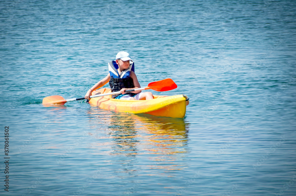 kayaking lessons. Boy with life buoy suit in kayak lessons during summer vacations in an island of Greece. kayaking lessons. Boy with life buoy suit in kayak lessons during summer vacations in an island of Greece.