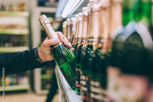 The guy is holding a bottle of champagne in the store.