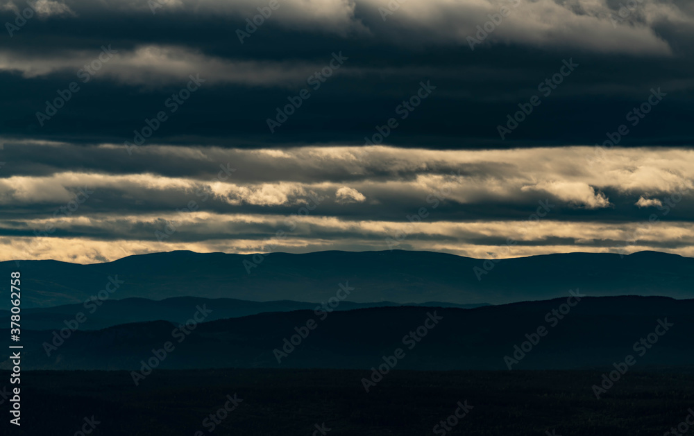 Panoramic view over dense woods and mountain terrain during sunset in Norway.