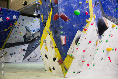 Artificial rock climbing wall for workout indoors with coloured grips and route markers.