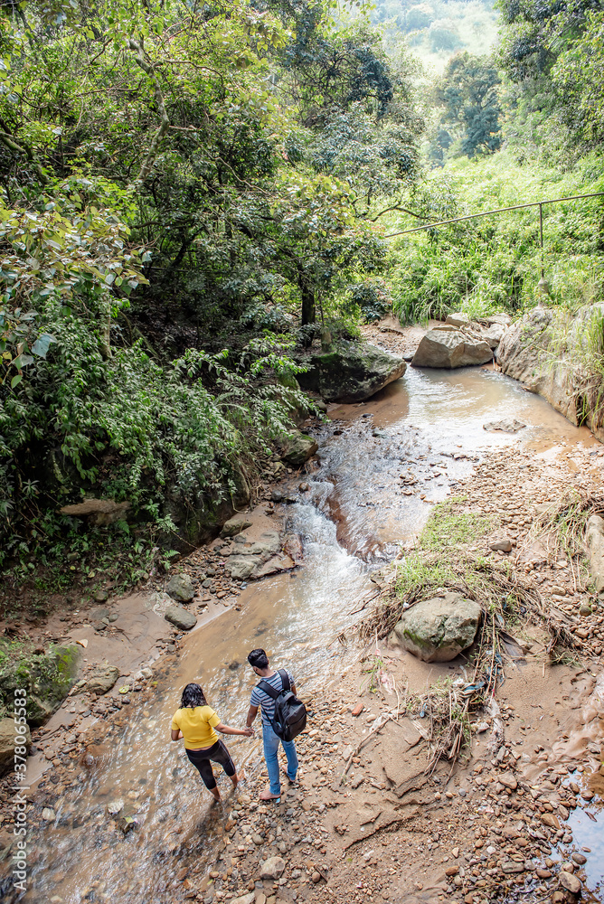 A young couple walks near a mountain stream in the jungle on the island of Sri Lanka