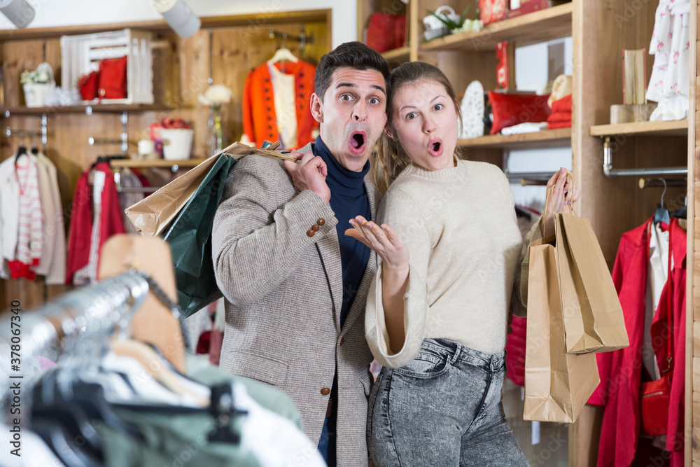 Young woman and man are standing satisfied with packadge after shopping in the clothes store.