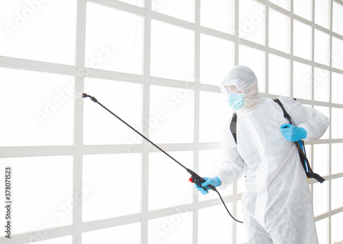 Asian male wear protective suit with spray device for sterilizing inside a building or office,To prevent spread of disease from crisis of coronavirus (COVID‑19) outbreak.New normal concept. © zawiftduck