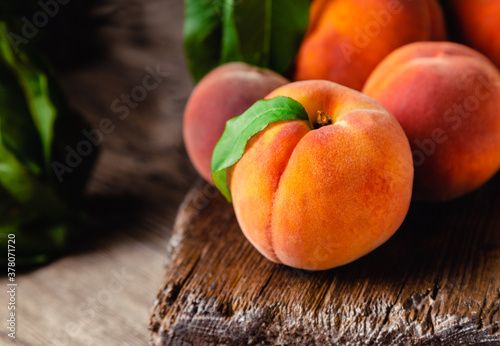 Peach fruit with leaf. Ripe juicy orange peach fruit of peach tree on wooden cutting rustic board. Peach harvest closeup in dark key.