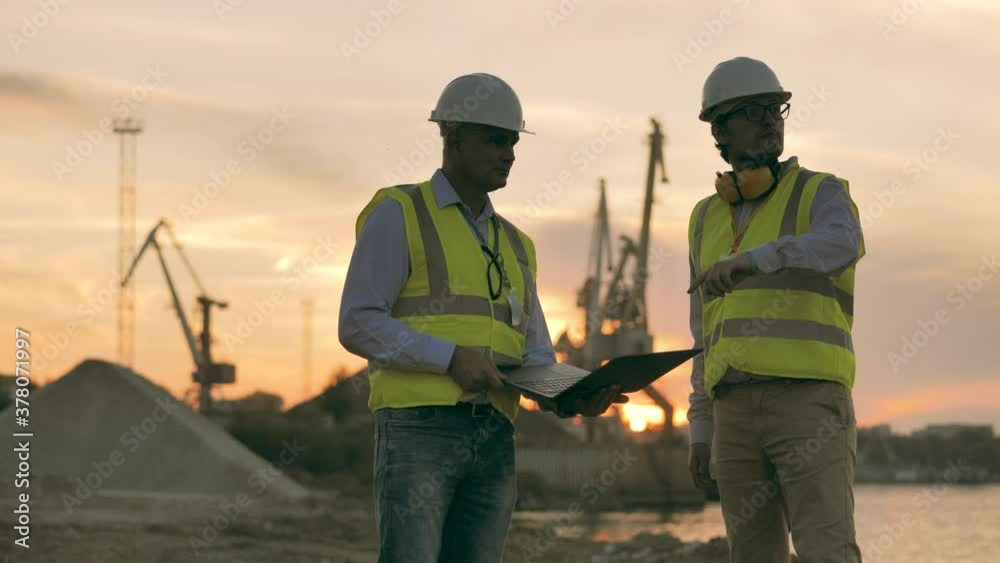 Loading port with two engineers having a discussion at sunset Loading port with two engineers having a discussion at sunset