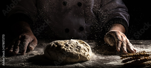 Chef-kok handen koken deeg op donkere houten achtergrond. Witte bloem die de lucht in vliegt. Voedselconcept