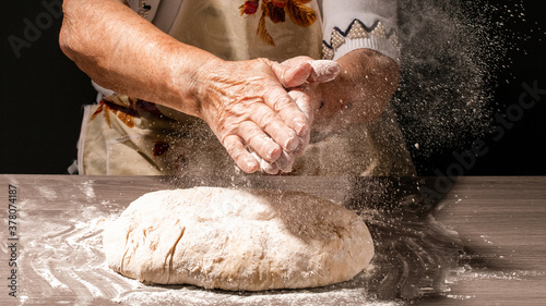 Photo of flour and women hands with flour splash. Cooking bread. Kneading the Dough. Isolated on dark background. Empty space for text