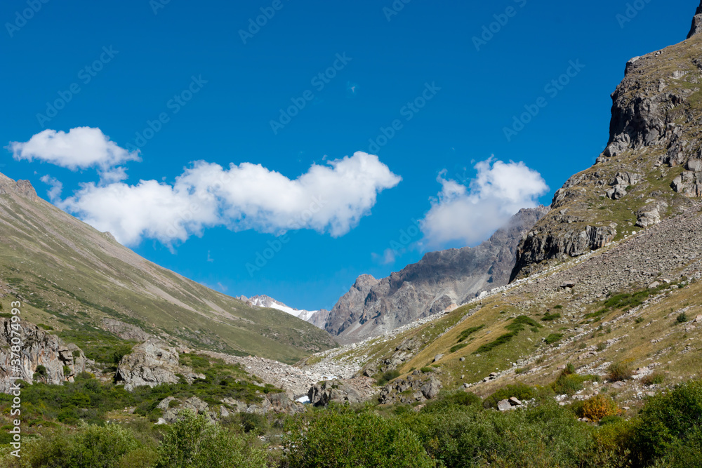 Mountain landscape view in Kyrgyzstan. Green grass in mountain valley view. Mountain panorama.