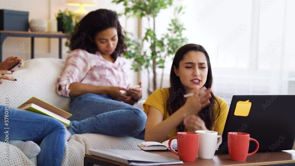 Diverse women students studying at home, Arabian girl using laptop and getting bad news. Caring roommates cheering her up. Concept of support Diverse women students studying at home, Arabian girl using laptop and getting bad news. Caring roommates cheering her up. Concept of support