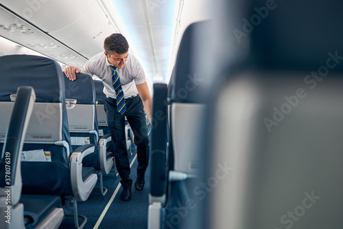 Confident male working on the empty salon of passenger airplane