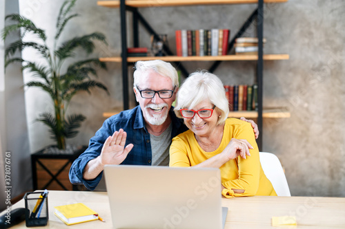 A happy senior couple is talking online via video connection on the laptop