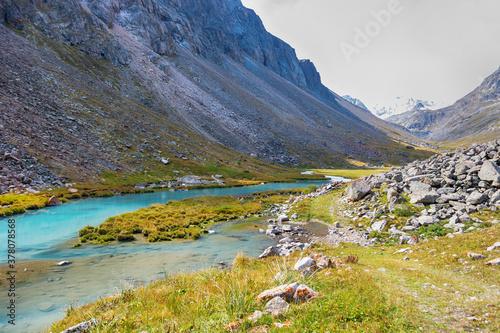 Idyllic summer landscape with hiking trail in the mountains with beautiful fresh green mountain pastures  river.