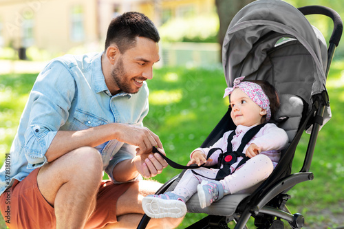 family, fatherhood and people concept - happy father with child or baby daughter in stroller at summer park © Syda Productions