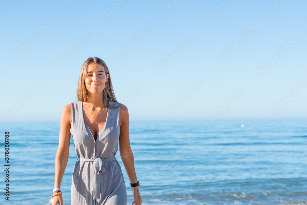 Woman walking on the beach in a green dress. Sea background.