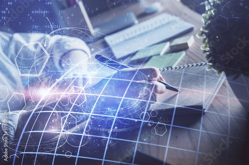 Double exposure of hands making notes with world map hologram and data theme icons. Concept of international network data.