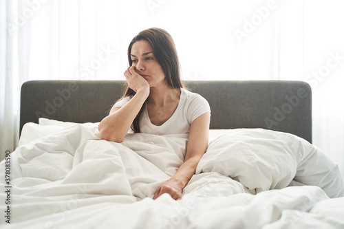 Sad thoughtful female sitting in a bedroom