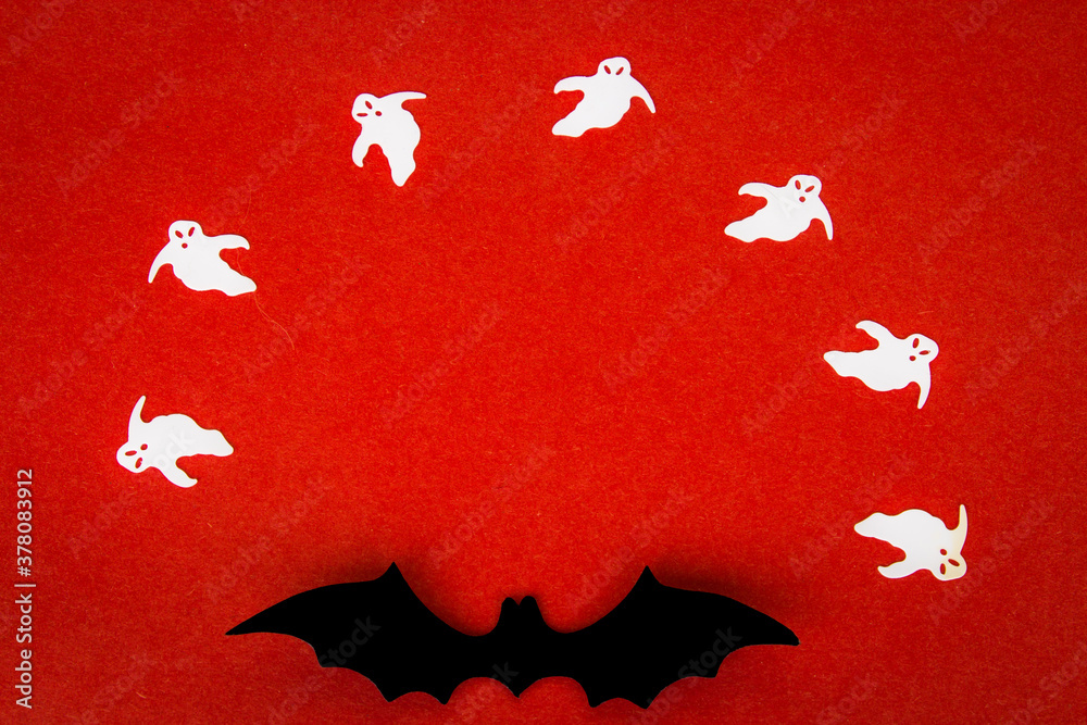 Halloween background. Ghosts and a bat on a red background. Halloween decor. Copy space. Halloween background. Ghosts and a bat on a red background. Halloween decor. Copy space.