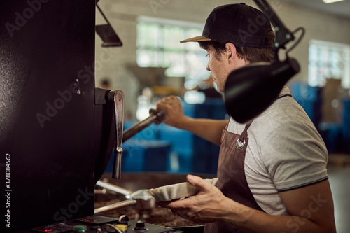 Male worker using industrial coffee roasting machine