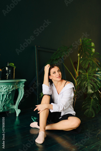 Portrait of a beautiful young woman in a white shirt and black pants in the Studio