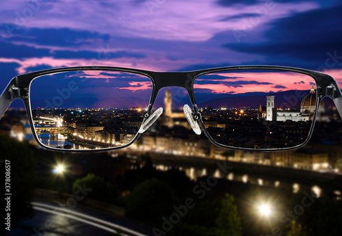 Focused image of night view of Florence, Italy. Better vision concept. Through glasses frame. Colorful view of landscape in glasses.