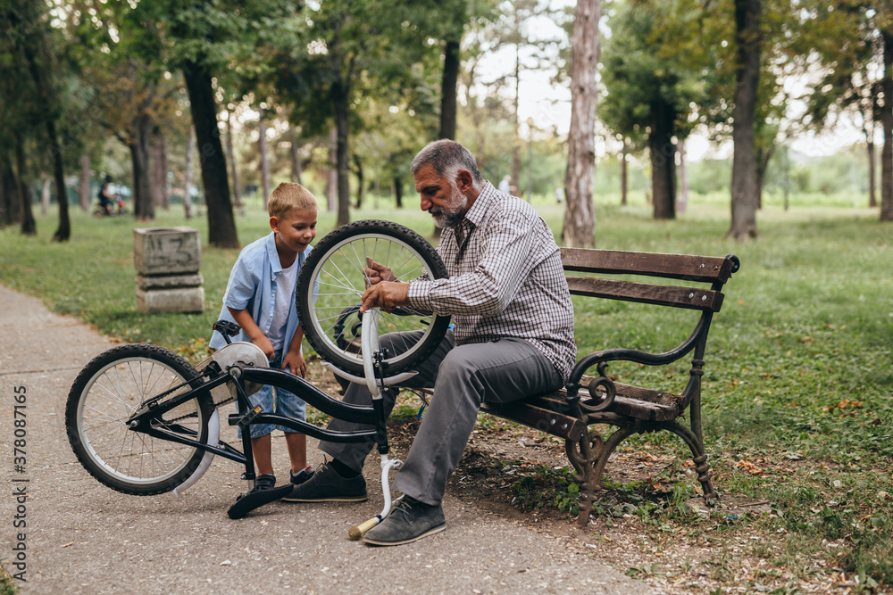 grandfather with his grandson at the city park fixing bicycle grandfather with his grandson at the city park fixing bicycle