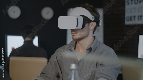 Game designer wearing VR headset and working in augmented reality in office