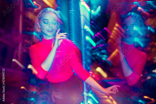 Young forever. Cinematic portrait of stylish young woman in neon lighted room. Bright neoned colors. Caucasian model, musician outdoors. Youth culture in party, festival style and music concept.