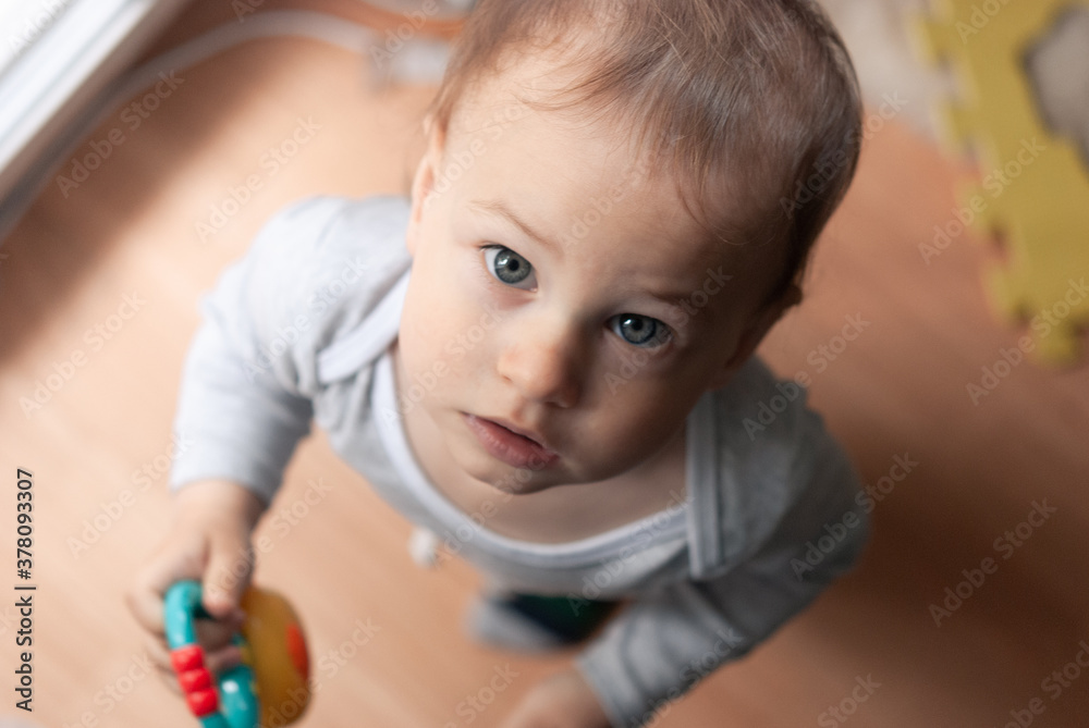 Little boy looks surprised up into the camera. Shooting from above. Child 1 year old boy indoor. Little boy looks surprised up into the camera. Shooting from above. Child 1 year old boy indoor.