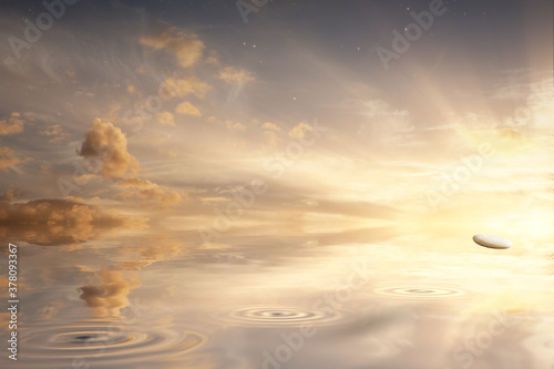 Stone skipping across a calm ocean with sunrise photo