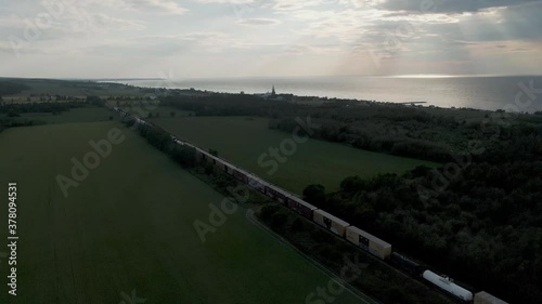 Wallpaper Mural Long Train Passing By On The Railway Through The Green Field In Northern Quebec, Canada. Ray Of Sunlight By The Sea In The Background - aerial drone, ascending shot Torontodigital.ca
