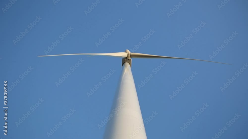Wind mill with rotating wings on the background of blue sky Wind mill with rotating wings on the background of blue sky