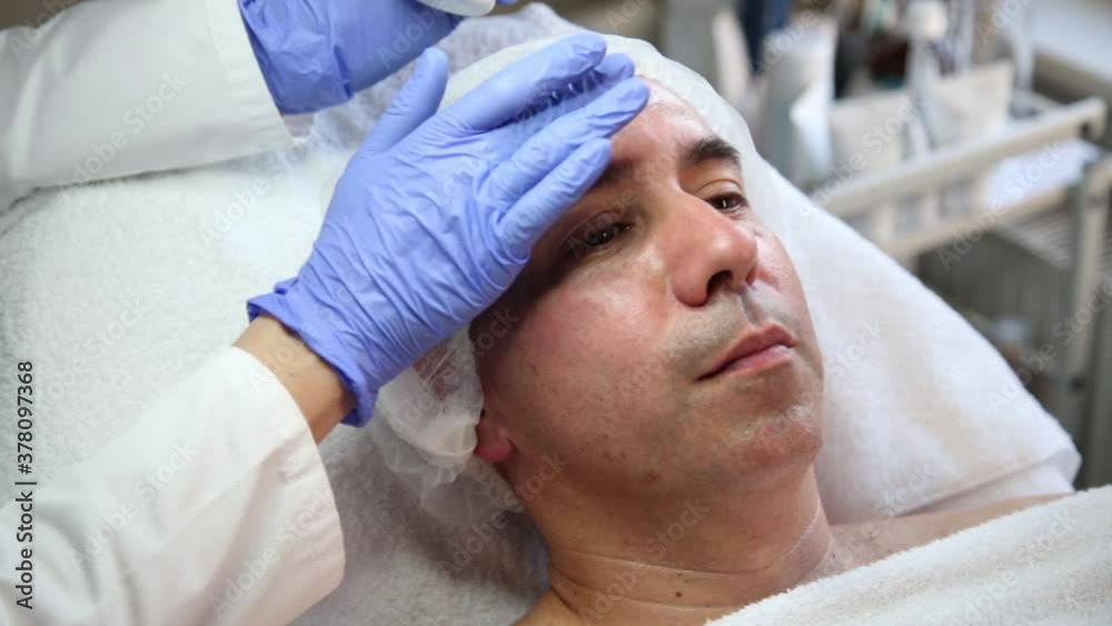 Beautician applies cream on man's face Beautician applies cream on man's face