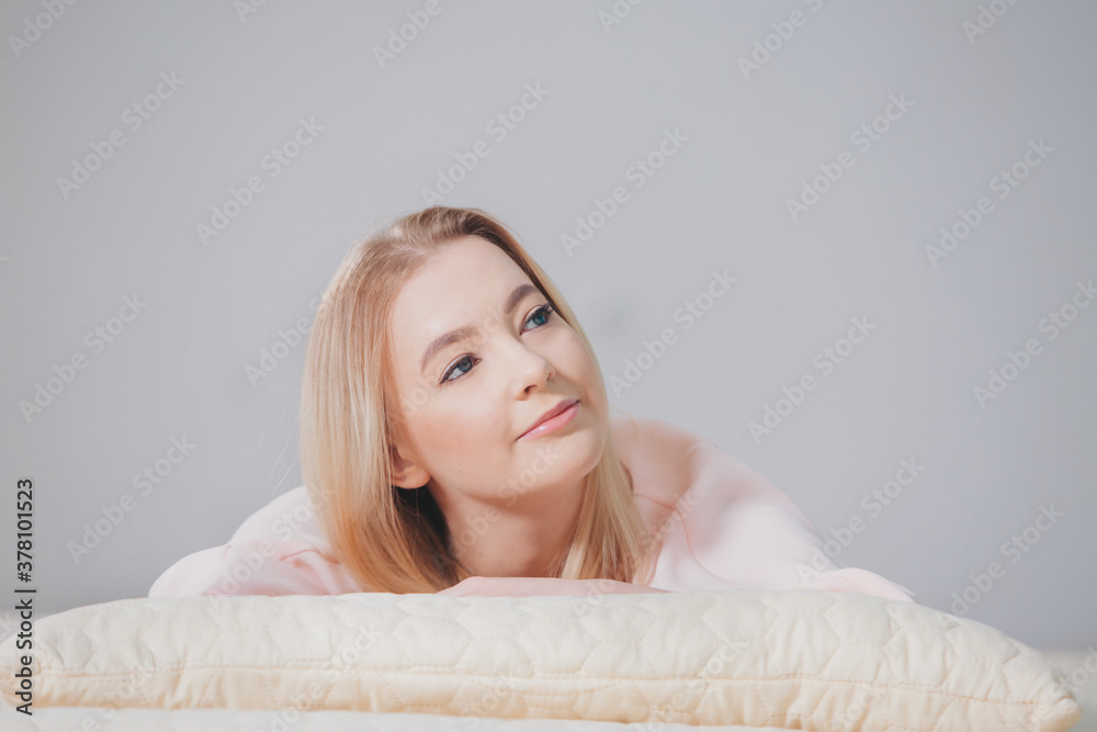 Fototapeta premium the blonde in pink is lying on the floor. the girl smiles. beauty and health of the face, hair, and skin. copy space