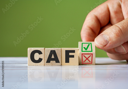 hand turn wooden block with red reject X and green confirm tick as change concept of CAF. Word CAF conceptual symbol. photo