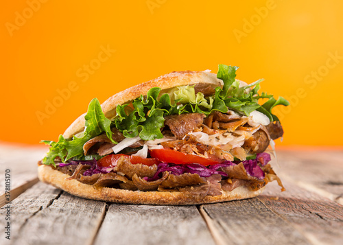 Turkish Doner Kebab Sandwich on wooden background, close-up.