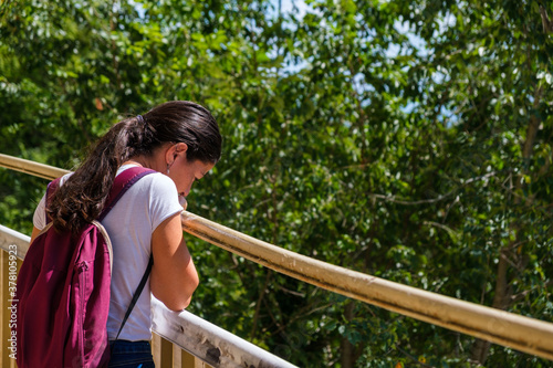 young woman leaning on a handrail and looking down from high rock