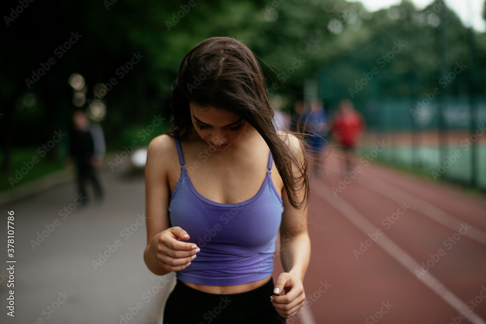 Beautiful woman training on running track. Young woman in blue sportswear listening the music. Beautiful woman training on running track. Young woman in blue sportswear listening the music.