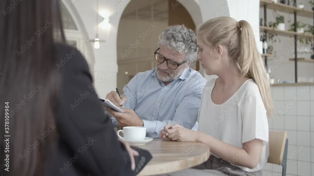 Agent and customers meeting in co-working space, signing health insurance agreement, shaking hand and smiling. Medium shot. Contract and expertise concept Agent and customers meeting in co-working space, signing health insurance agreement, shaking hand and smiling. Medium shot. Contract and expertise concept