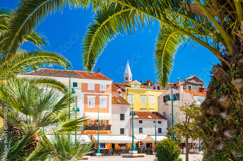 Town of Mali Losinj on the island of Losinj, Adriatic coast in Croatia, cathedral tower and city center, view through the palm leaves
