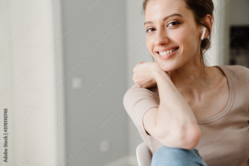 Photo of pleased girl in earphone smiling and looking at camera Photo of pleased girl in earphone smiling and looking at camera