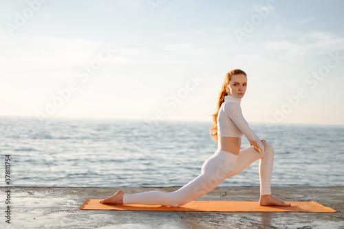 Image of sportswoman doing yoga exercise while working out on promenade